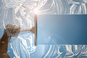 Window cleaner using a squeegee to wash a window with clear blue sky